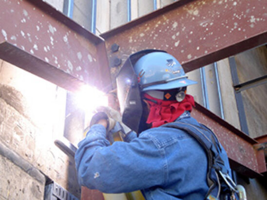 Welder working on a steel beam at a J.B. Steel project site in Arizona.